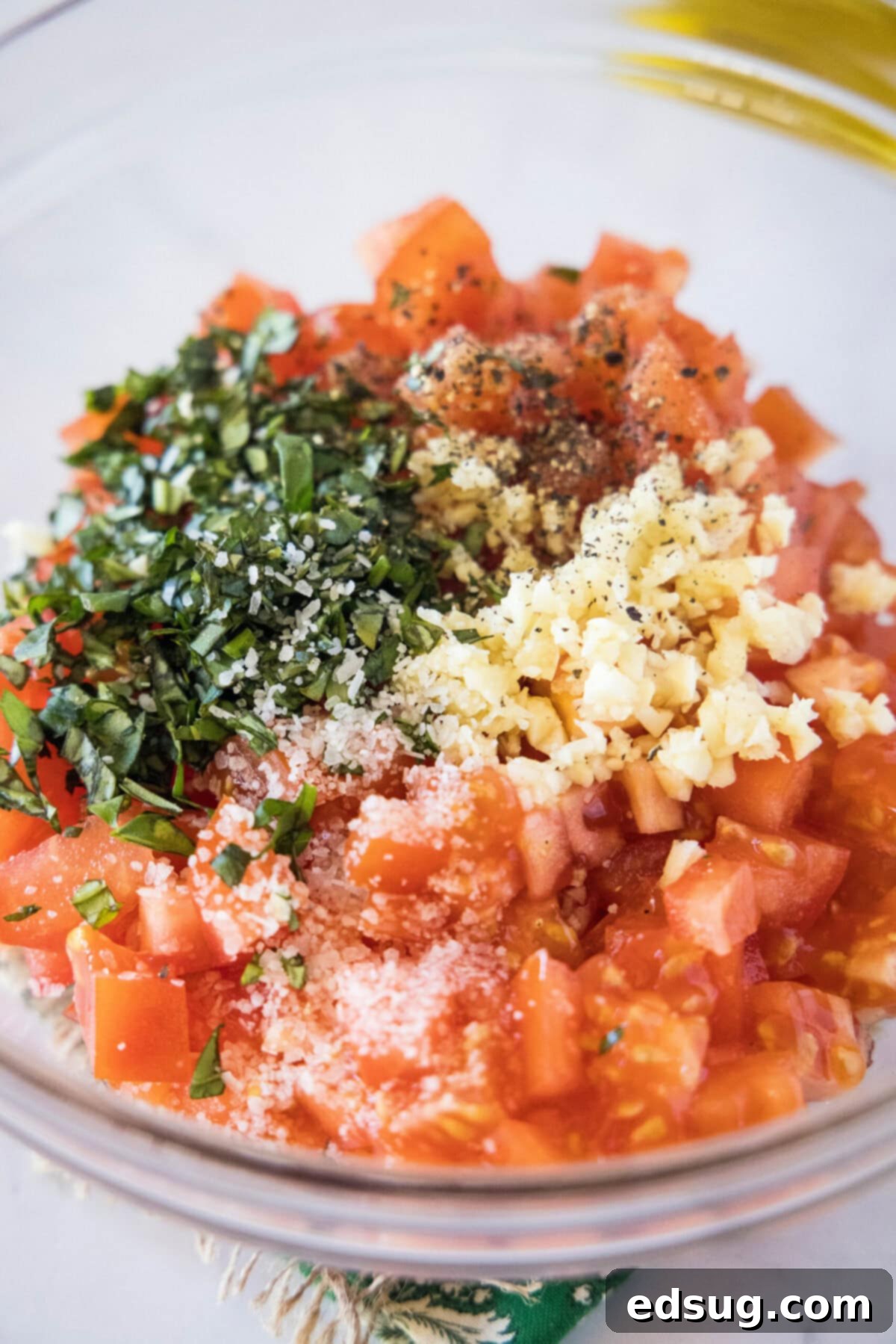 This easy bruschetta is the perfect appetizer or party food. It's loaded with tomatoes, garlic, and basil, and only takes 5 minutes. A bowl filled with tomato slices, garlic, salt, pepper, and basil