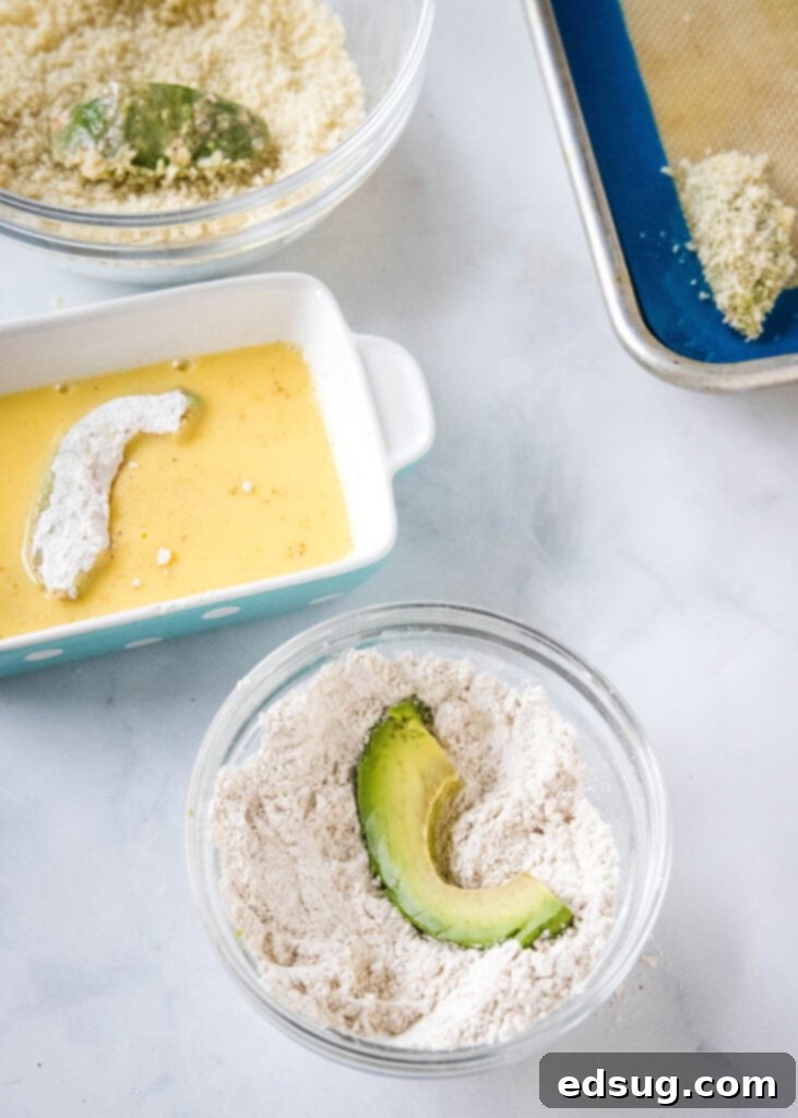 Avocado fries are crispy on the outside and warm and creamy on the inside, made in the air fryer (or oven). Don't forget the dipping sauce! Overhead view of a breading station with bowls of seasoned flour, egg wash, and panko breadcrumbs, ready for avocado slices.