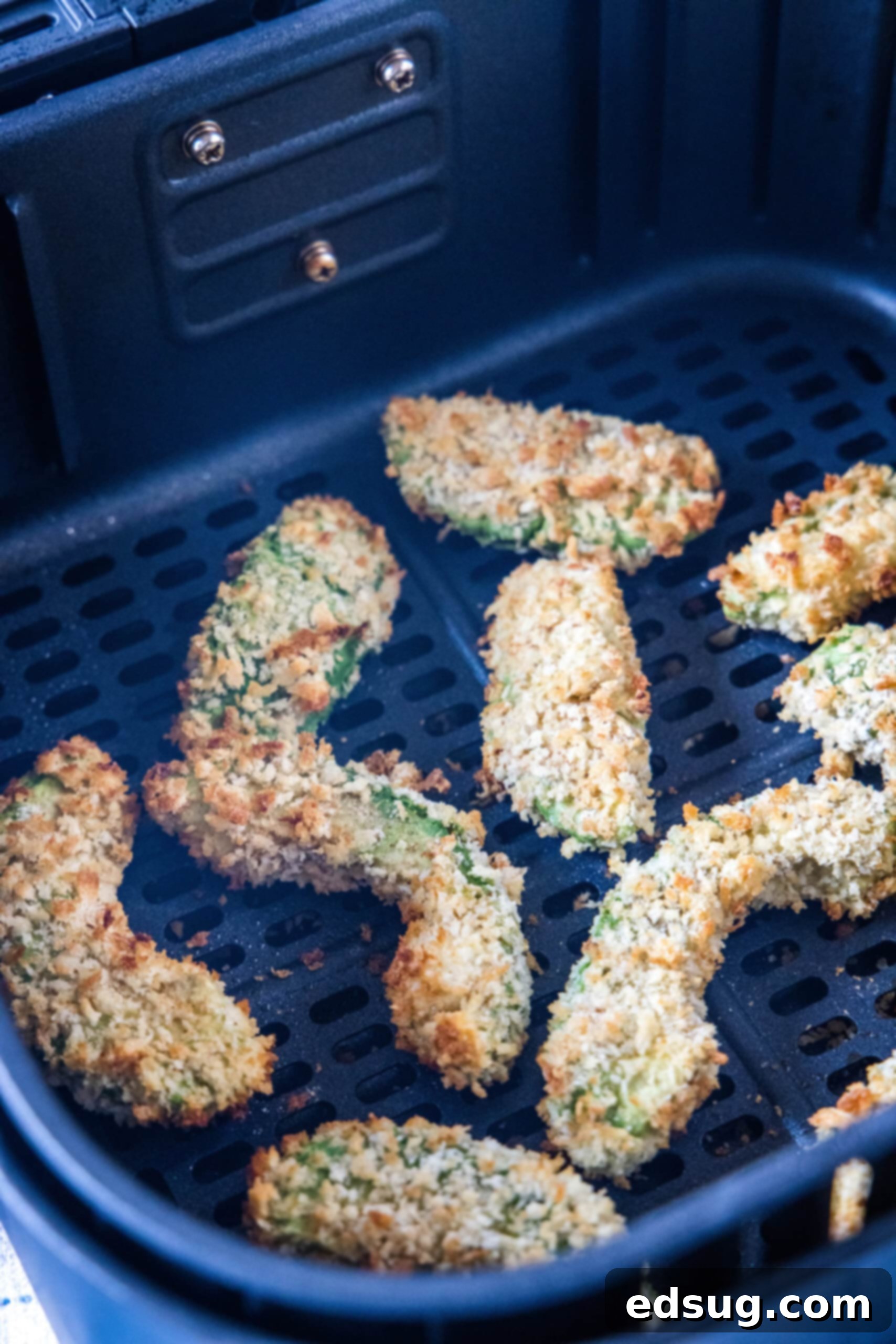 Avocado fries are crispy on the outside and warm and creamy on the inside, made in the air fryer (or oven). Don't forget the dipping sauce! Close-up of golden, crispy avocado fries nestled within an air fryer basket, freshly cooked.