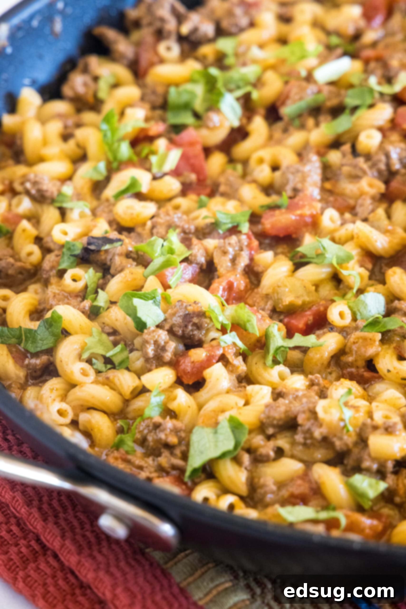 A large skillet filled with hot, bubbling taco mac and cheese, ready to be served.