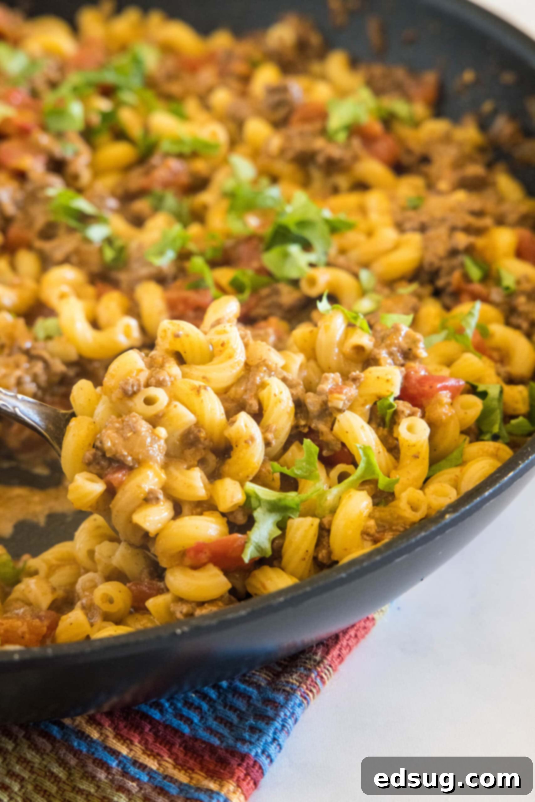 A close-up of the delicious taco mac and cheese in a large skillet, showing the cheesy texture.