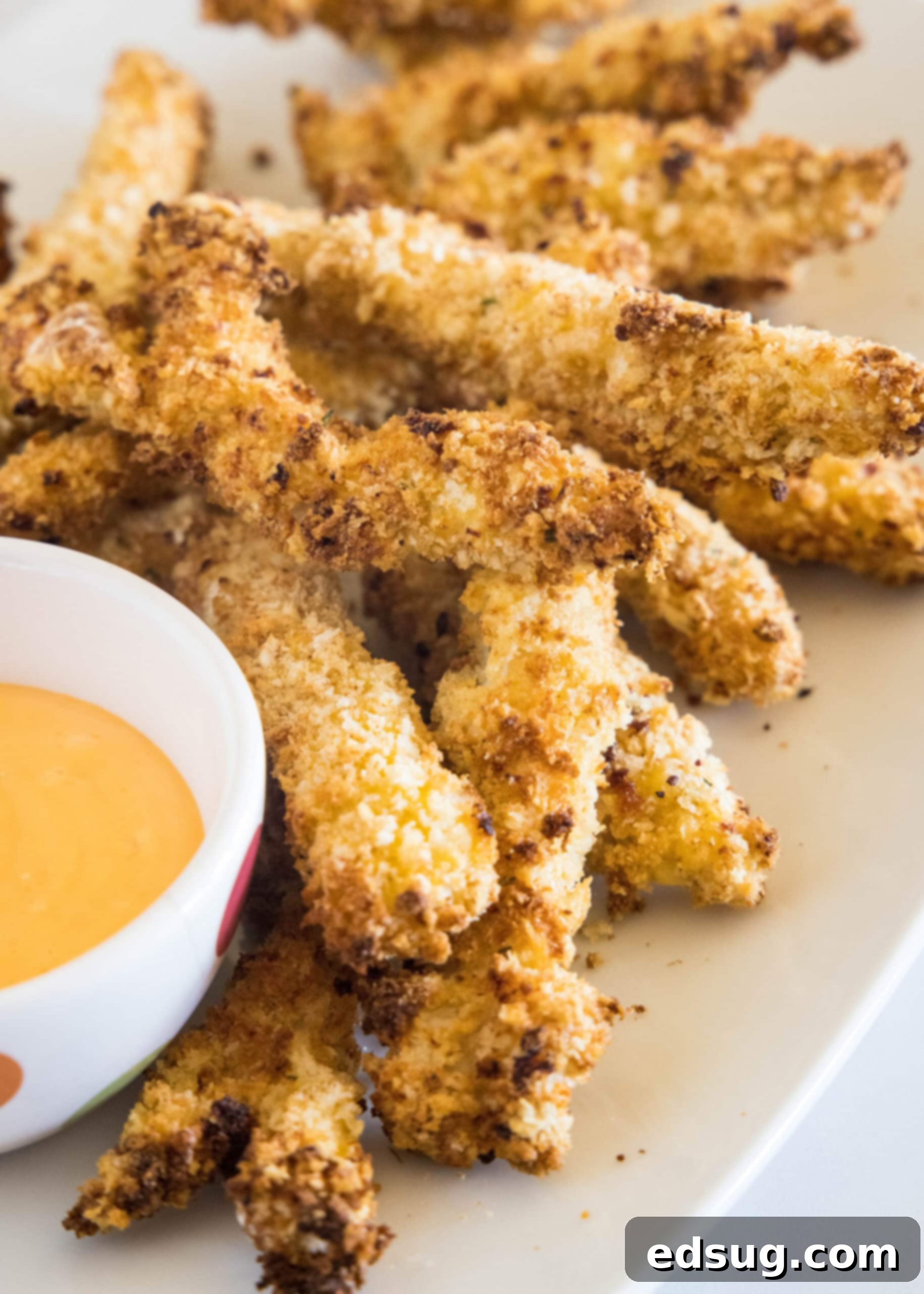 Juicy on the inside and crunchy on the outside, chicken fries are a seriously addictive appetizer or side. Ready for dipping in 20 minutes! Chicken fries on an oval platter next to a bowl of dipping sauce.