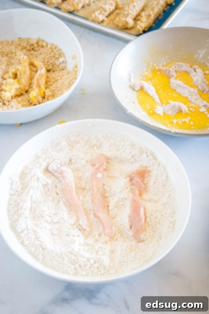Juicy on the inside and crunchy on the outside, chicken fries are a seriously addictive appetizer or side. Ready for dipping in 20 minutes! A breading station with chicken strips placed in bowls of flour, breadcrumbs, and egg wash.