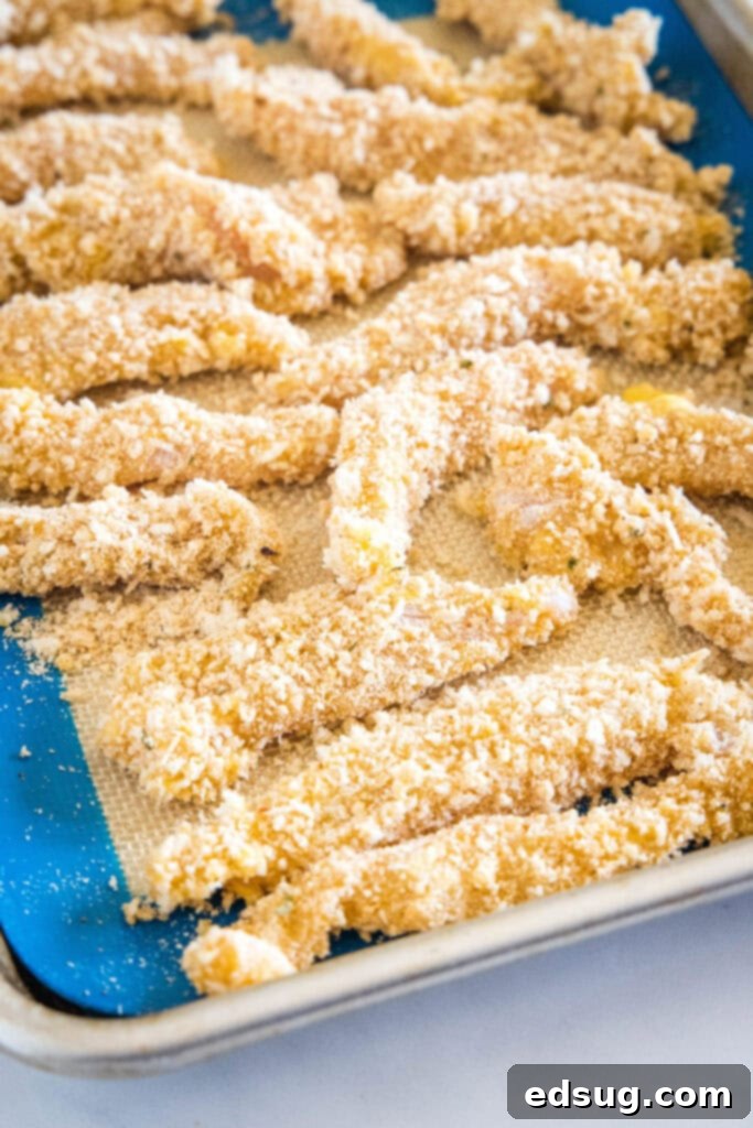 Juicy on the inside and crunchy on the outside, chicken fries are a seriously addictive appetizer or side. Ready for dipping in 20 minutes! Breaded chicken strips on a baking sheet.