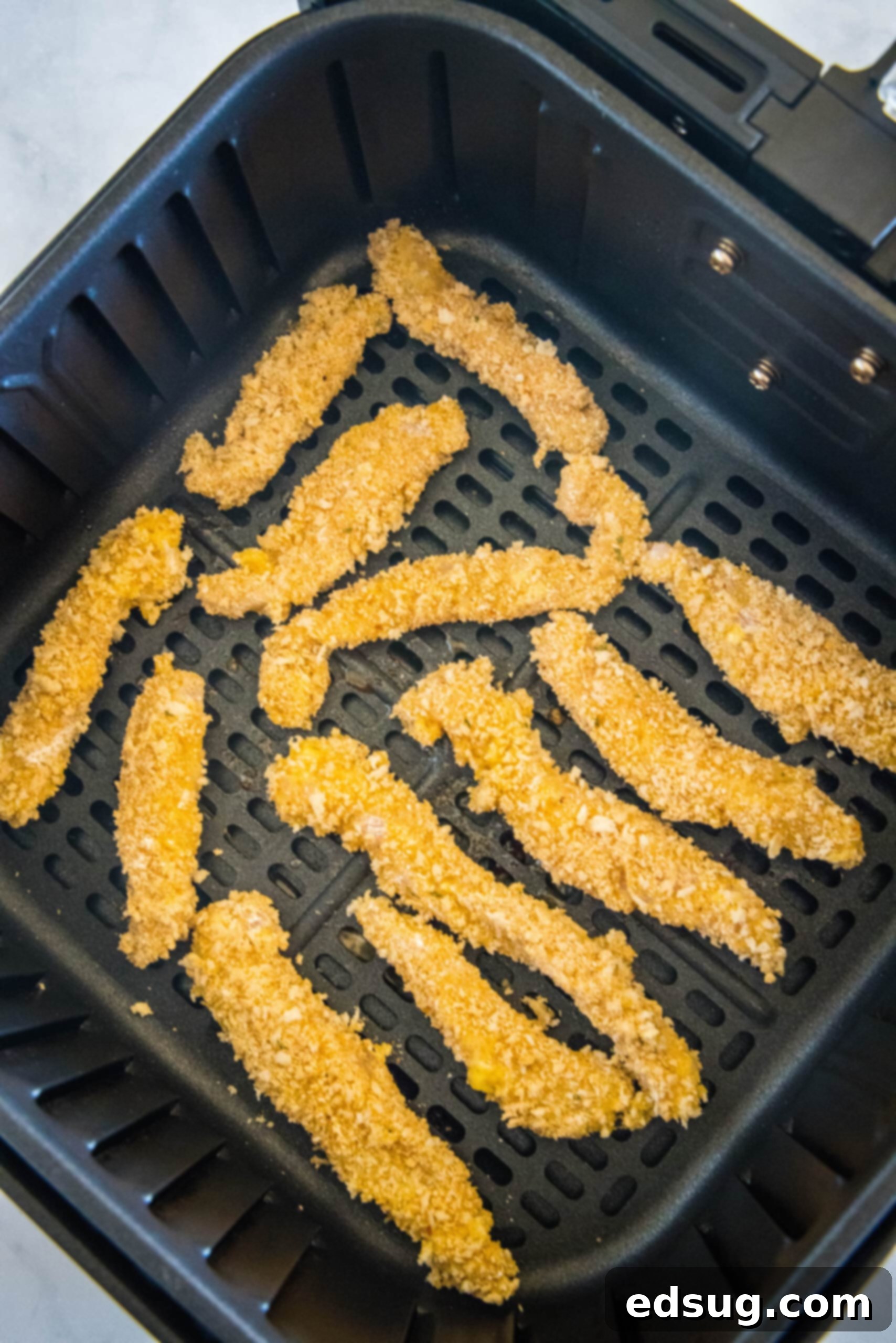 Juicy on the inside and crunchy on the outside, chicken fries are a seriously addictive appetizer or side. Ready for dipping in 20 minutes! Overhead view of chicken fries inside the air fryer basket.