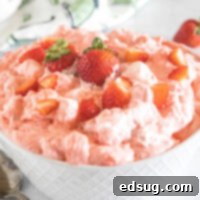 Strawberry fluff topped with chopped strawberries in a white bowl.