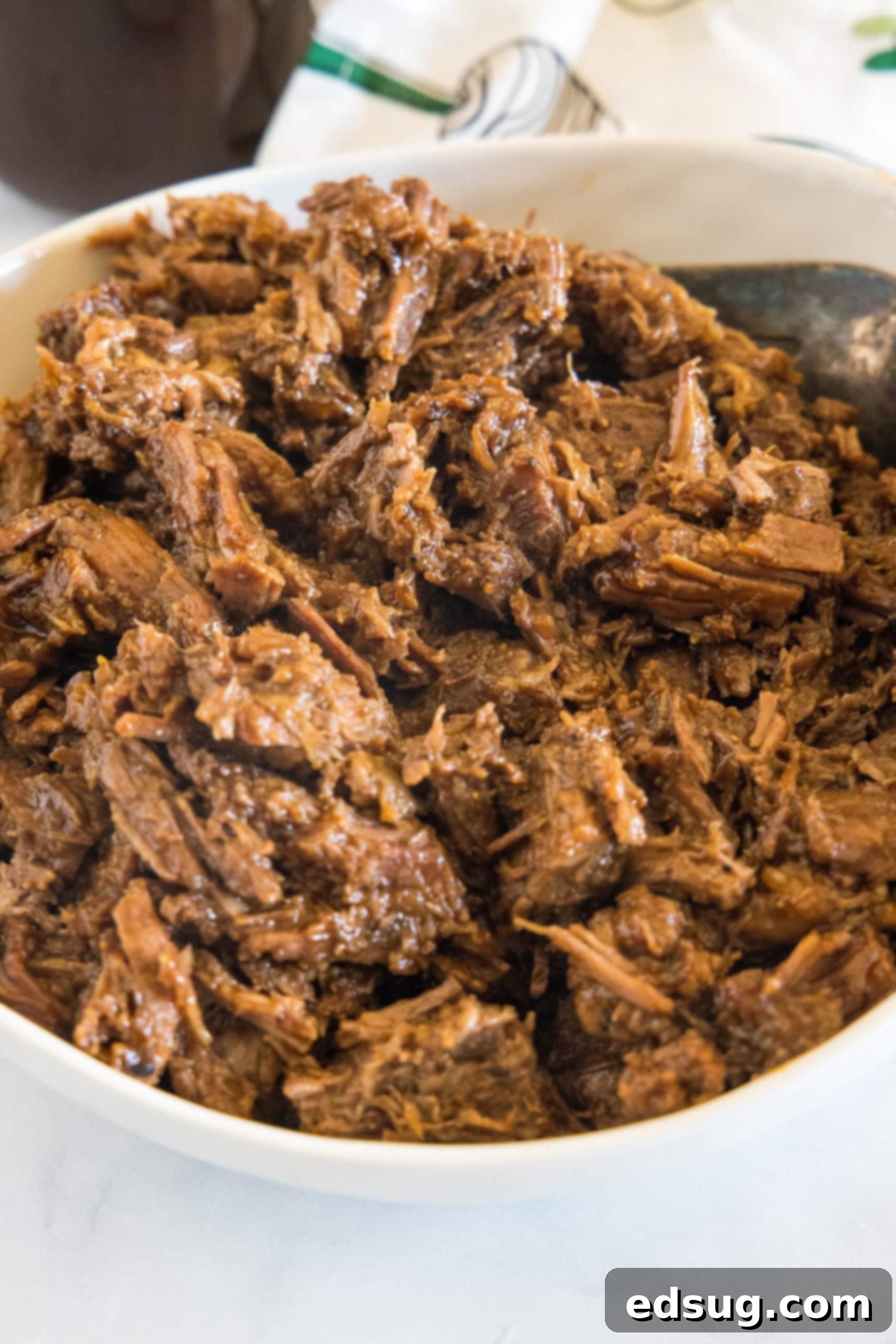 A large bowl filled with succulent shredded BBQ beef, glistening with sauce.