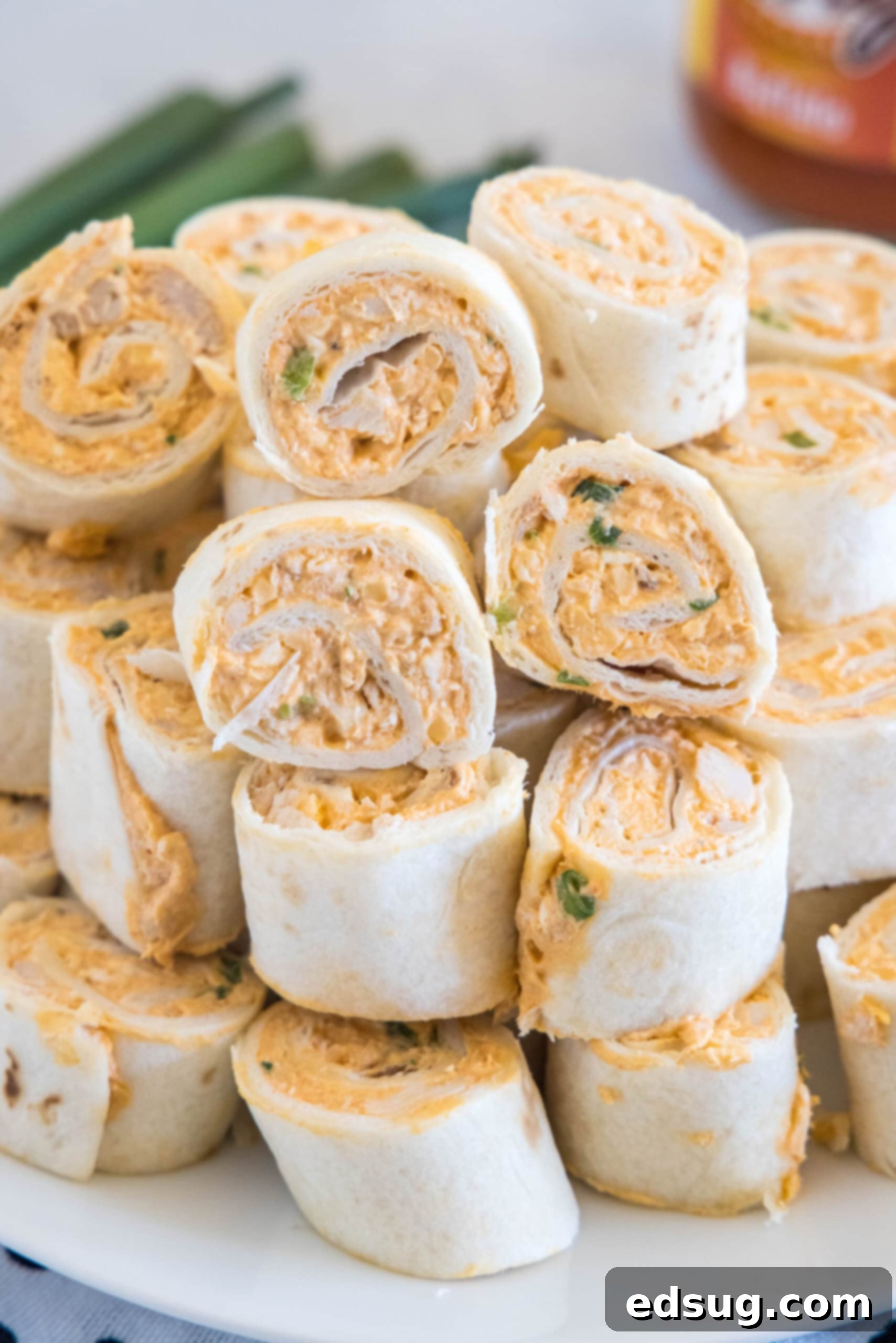 Buffalo chicken pinwheels are a quick and easy appetizer packed with bold Buffalo flavor. Roll up the spicy chicken filling, chill, and slice! Vibrantly arranged Buffalo chicken pinwheels stacked on a pristine white plate, showcasing their bold colors and enticing texture.