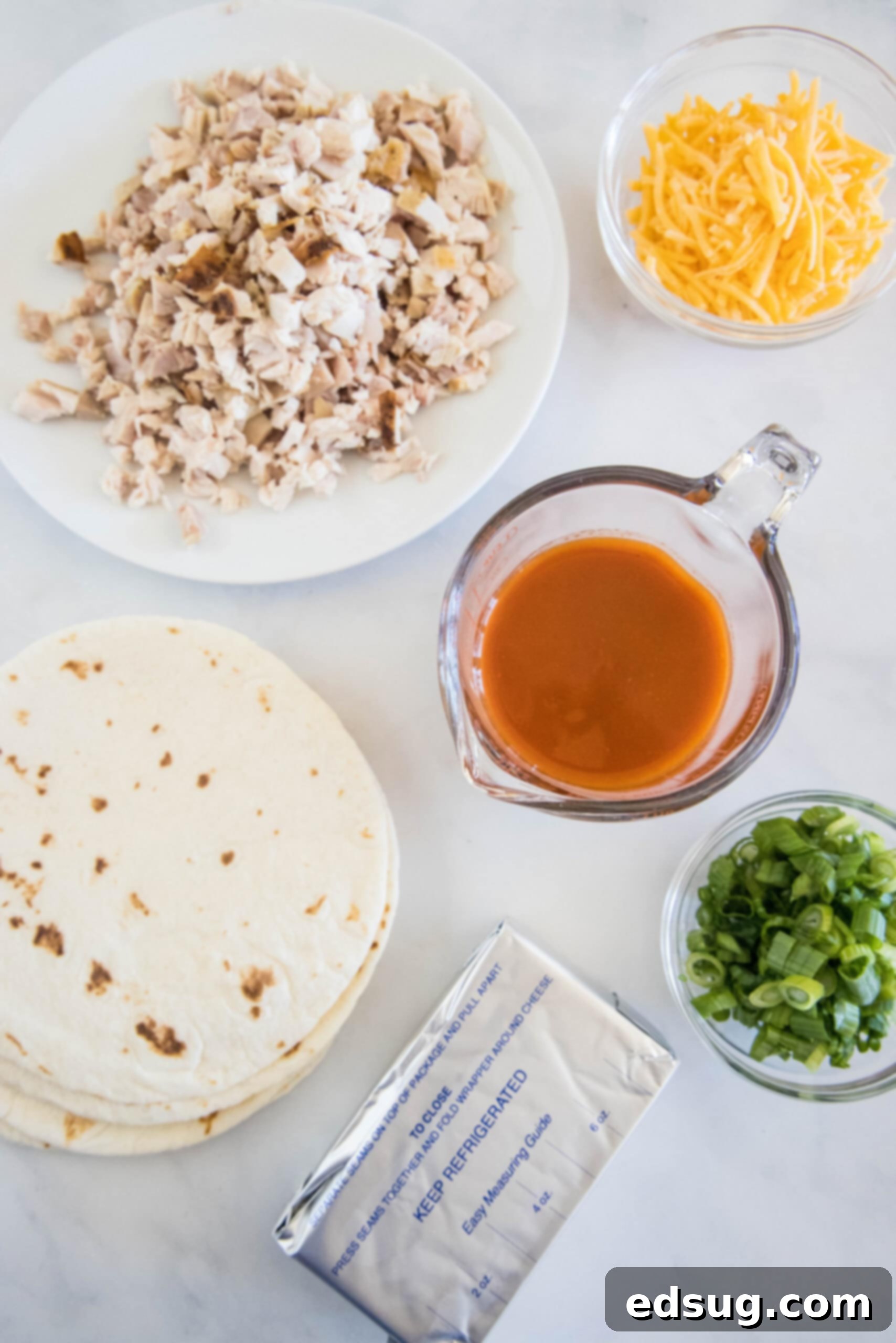 Buffalo chicken pinwheels are a quick and easy appetizer packed with bold Buffalo flavor. Roll up the spicy chicken filling, chill, and slice! A vibrant selection of fresh ingredients laid out, ready for making Buffalo chicken pinwheels, including chicken, cheeses, sauces, and tortillas.