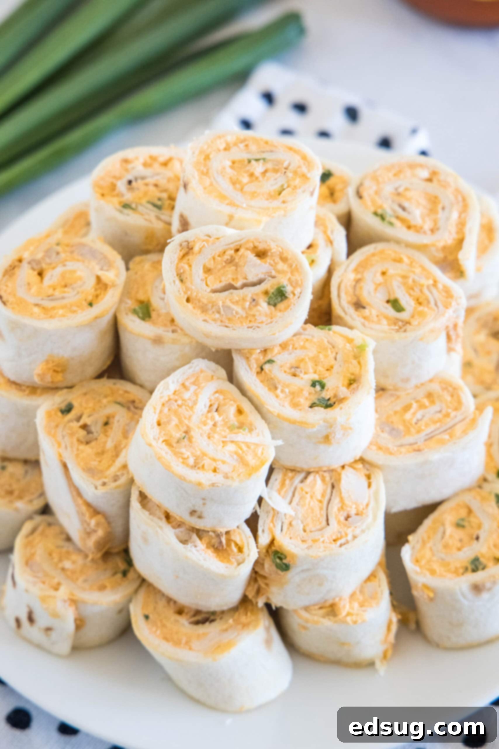 Buffalo chicken pinwheels are a quick and easy appetizer packed with bold Buffalo flavor. Roll up the spicy chicken filling, chill, and slice! A visually appealing stack of Buffalo chicken pinwheels, ready to be enjoyed, on a white plate, emphasizing their easy and delicious nature.
