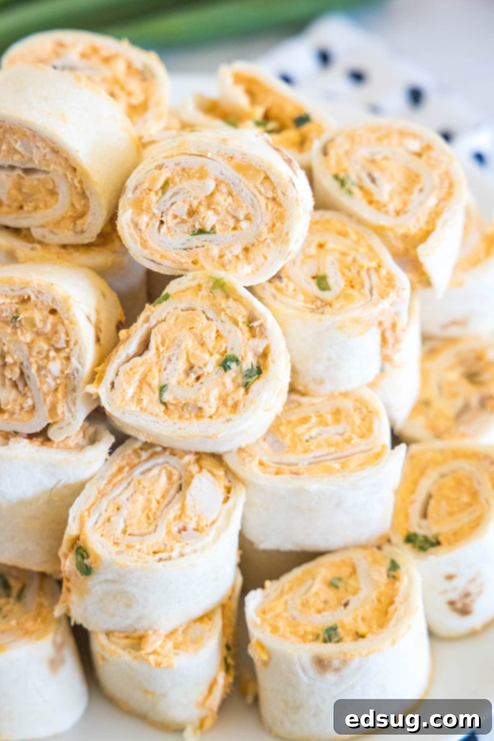 Buffalo chicken pinwheels are a quick and easy appetizer packed with bold Buffalo flavor. Roll up the spicy chicken filling, chill, and slice! A beautifully presented stack of Buffalo chicken pinwheels on a white plate, ready to be enjoyed as a delightful appetizer or snack.