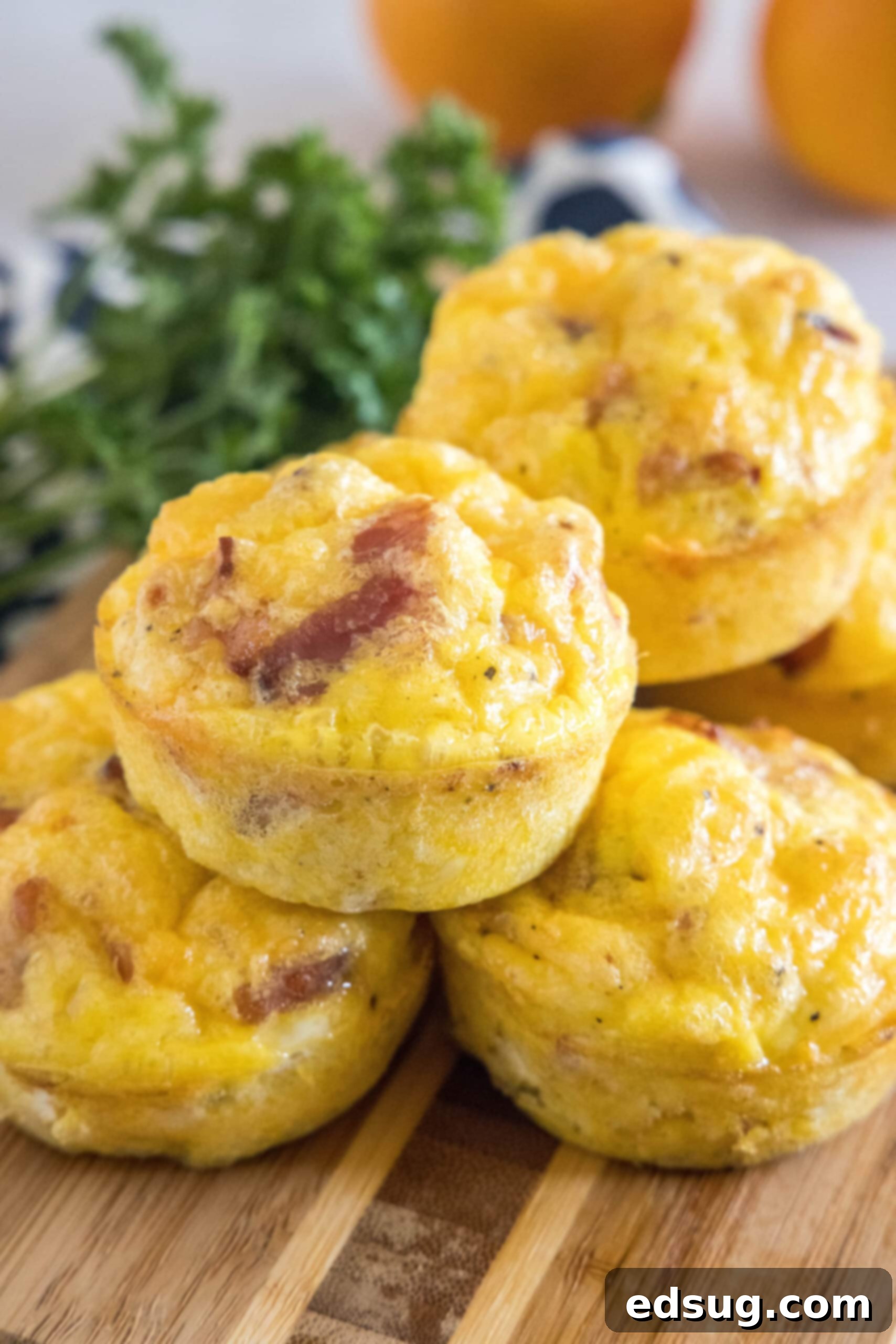 These bacon cheese egg muffins are packed with smoky crumbled bacon and melty cheddar. Enjoy these for brunch, or an easy on-the-go breakfast! Bacon cheese egg muffins stacked on a wooden cutting board.