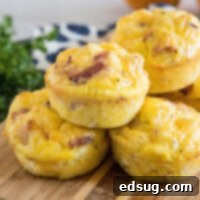 Cheesy Bacon & Egg Bites 2 Bacon cheese egg muffins stacked on a wooden cutting board.