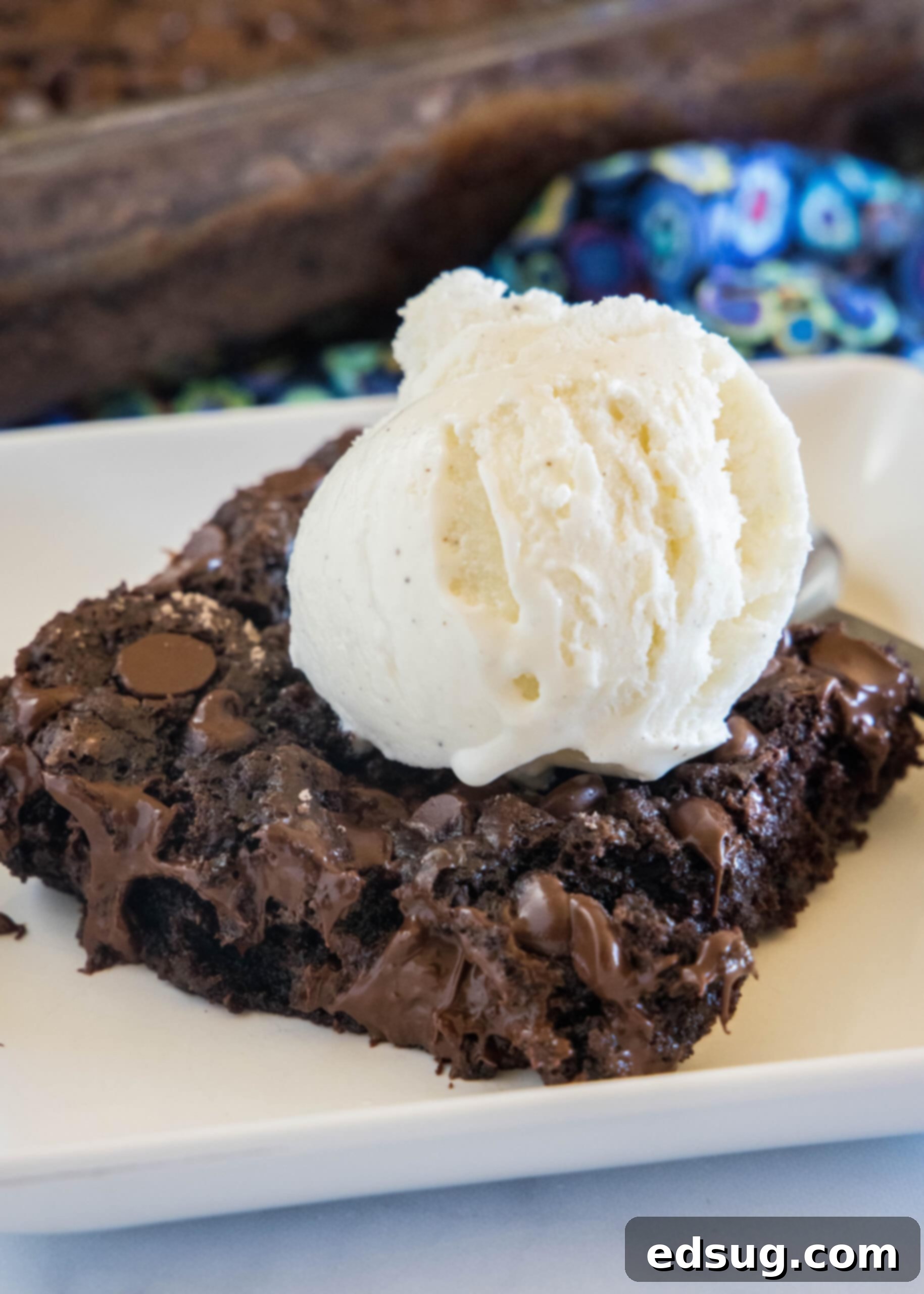 A slice of chocolate dump cake topped with a scoop of vanilla ice cream on a white plate.