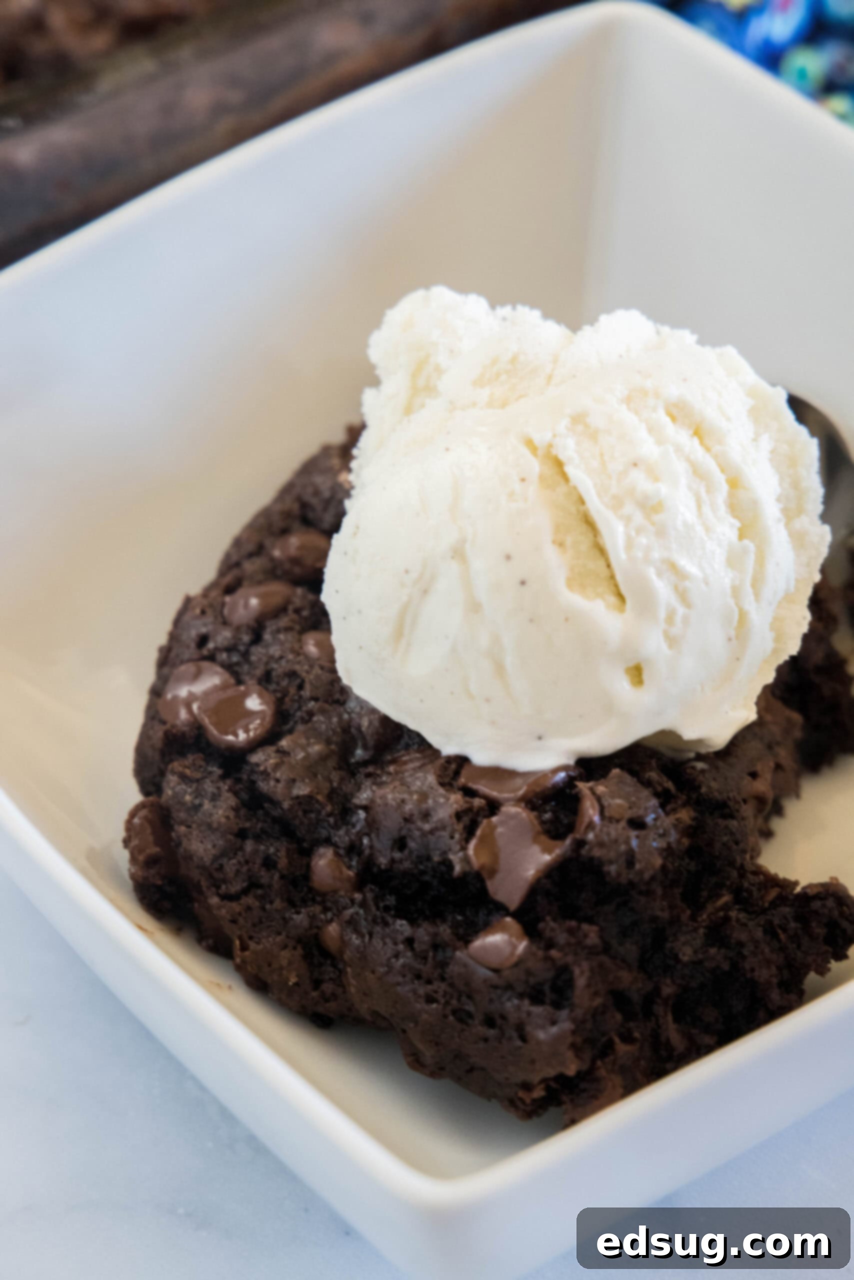 A slice of chocolate dump cake topped with a scoop of vanilla ice cream on a white plate.