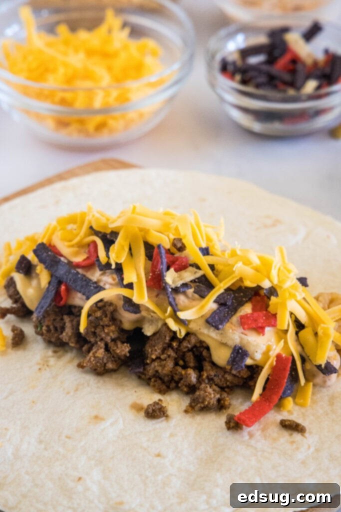 This copycat grilled cheese burrito recipe lets you remake an ooey-gooey Taco Bell favorite at home. Right down to the creamy chipotle sauce! Burrito ingredients layered onto a large flour tortilla.