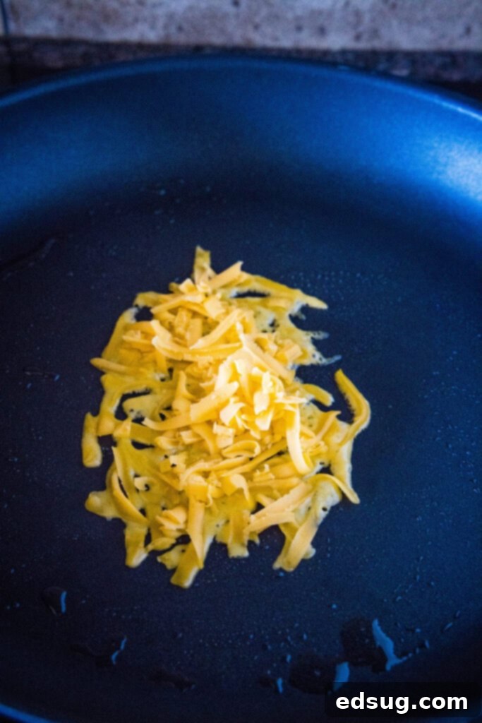 This copycat grilled cheese burrito recipe lets you remake an ooey-gooey Taco Bell favorite at home. Right down to the creamy chipotle sauce! A small pile of cheese in a skillet.