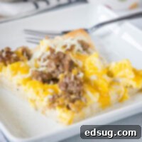 Morning Pie Perfection 2 A slice of breakfast pizza on a white plate next to a fork.