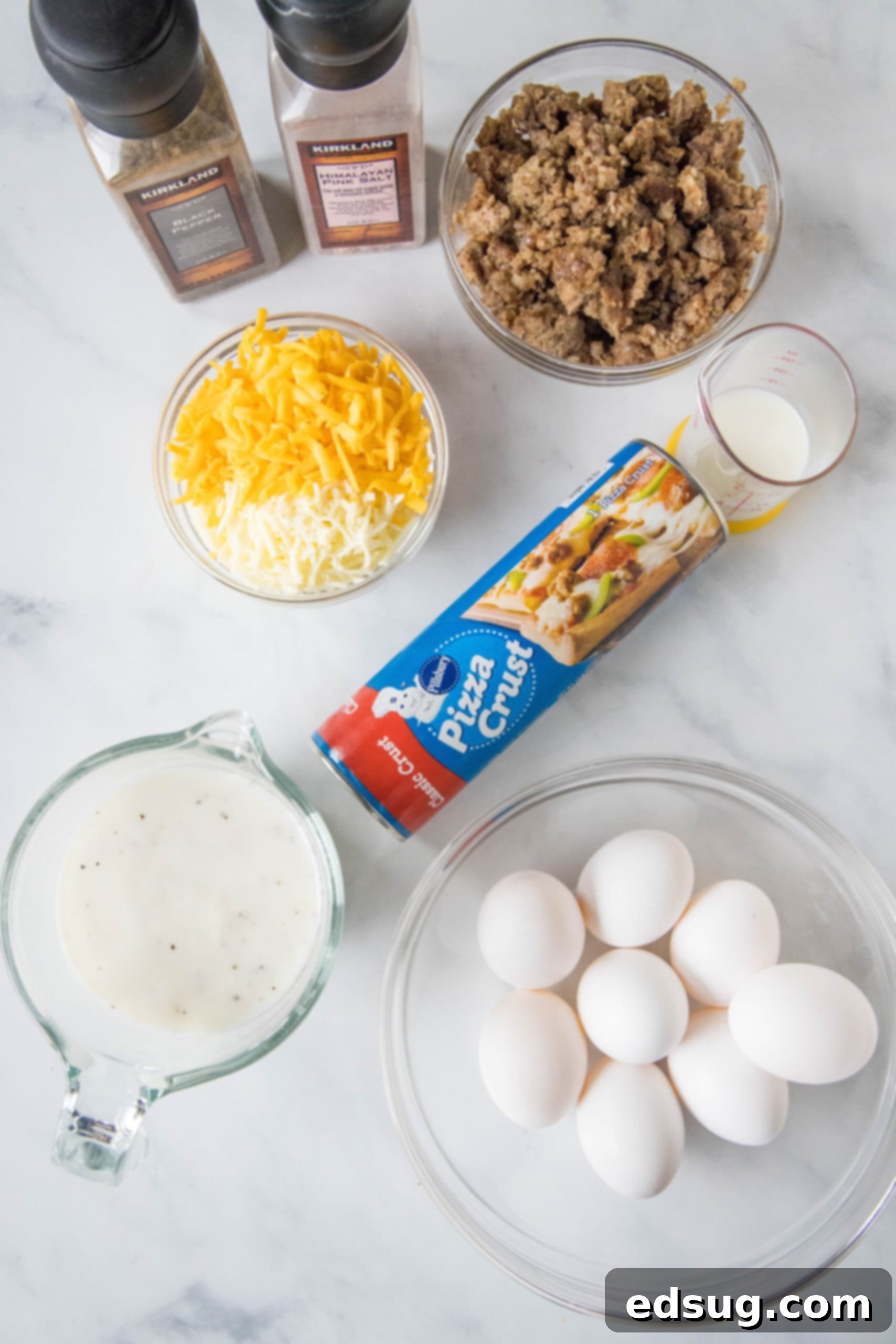 This satisfying breakfast pizza combines all of your breakfast favorites on top of a crispy pizza crust. It's so easy, baked in a sheet pan! Various ingredients for a sausage, egg, and cheese breakfast pizza laid out on a kitchen counter.