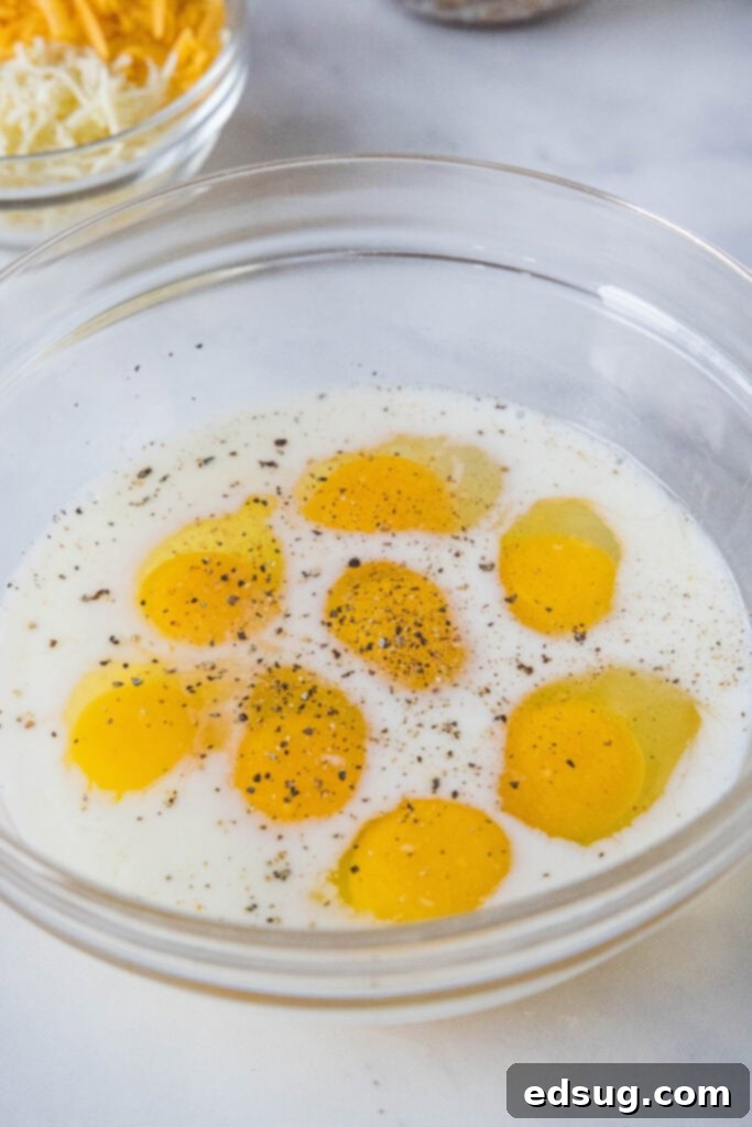 This satisfying breakfast pizza combines all of your breakfast favorites on top of a crispy pizza crust. It's so easy, baked in a sheet pan! Eggs combined in a mixing bowl with milk, salt, and pepper, ready for scrambling.