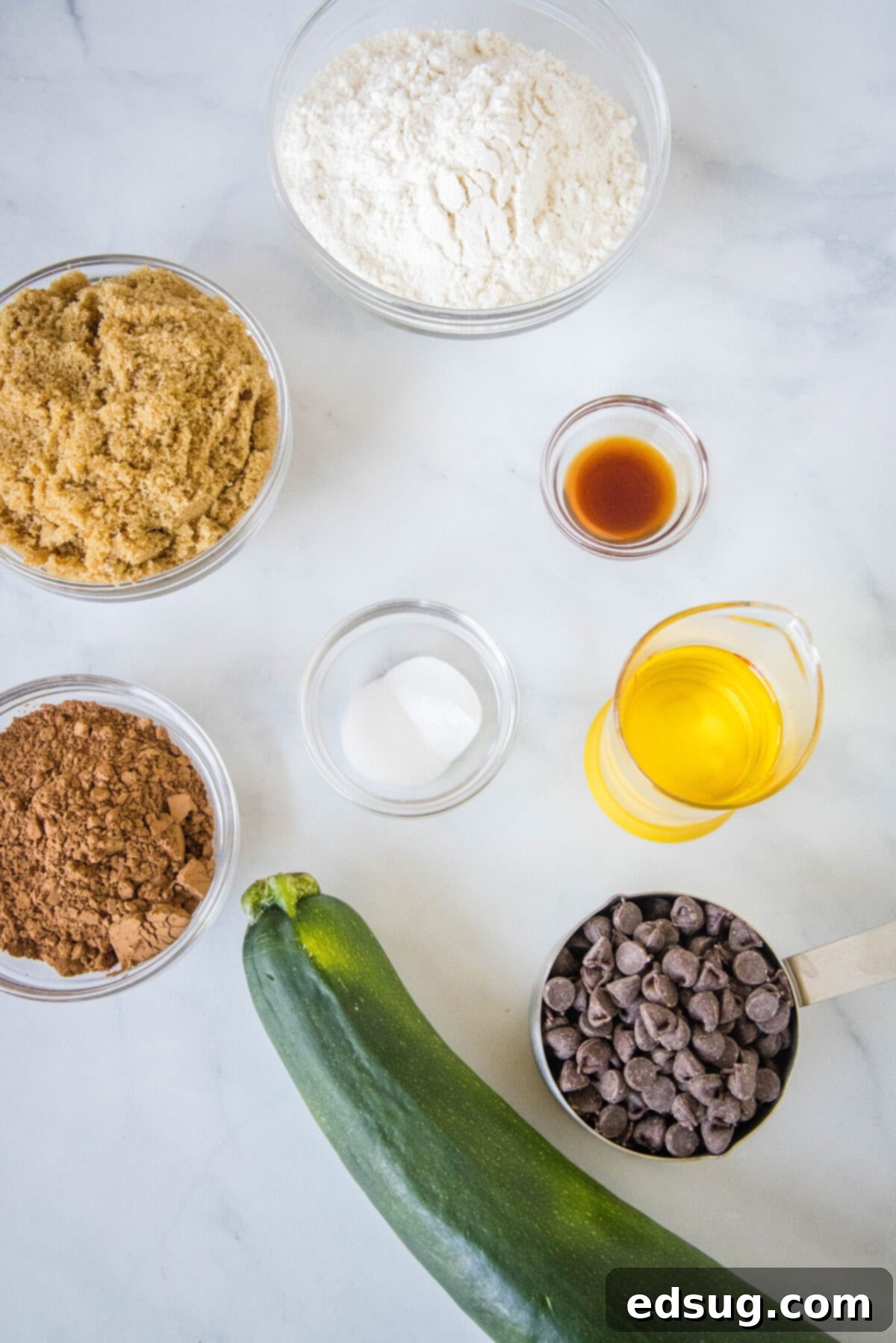 ingredients laid out for zucchini brownies: brown sugar, oil, vanilla, flour, cocoa, salt, baking soda, shredded zucchini, milk, chocolate chips