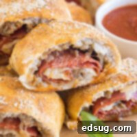 Cheesy Pizza Bread 2 Pizza bread slices stacked on a wooden board next to a bowl of pizza sauce for dipping.