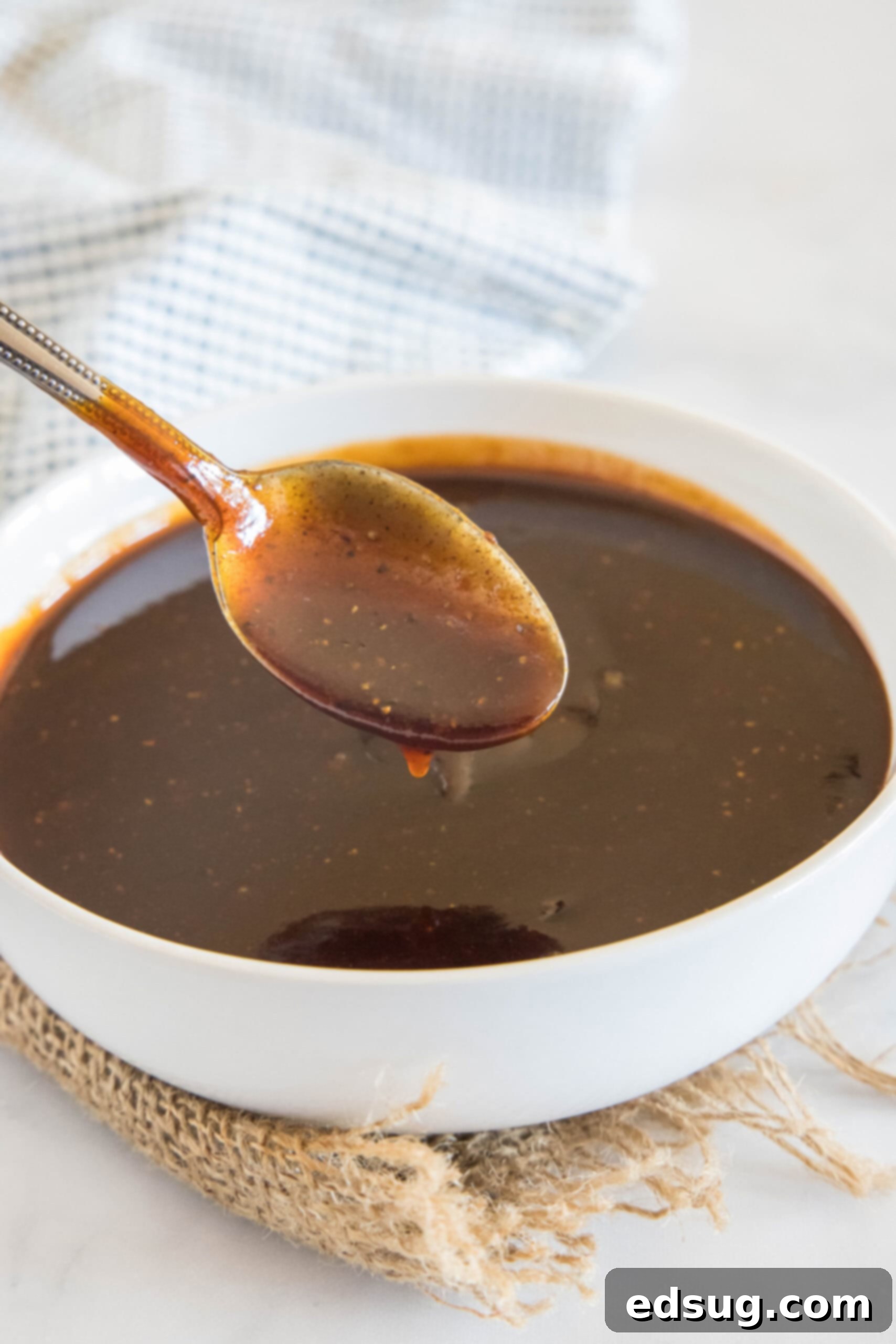 This easy homemade barbecue sauce tastes way better than store-bought! It’s sweet, tangy, and perfect on wings, ribs, grilled meat, and more. A spoonful of homemade barbecue sauce held over a bowl of sauce.