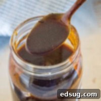 Signature Homemade Barbecue Sauce 2 A spoonful of homemade barbecue sauce held over a mason jar.