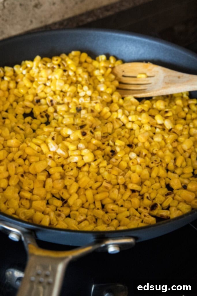 Sweet corn kernels cooking in a skillet.