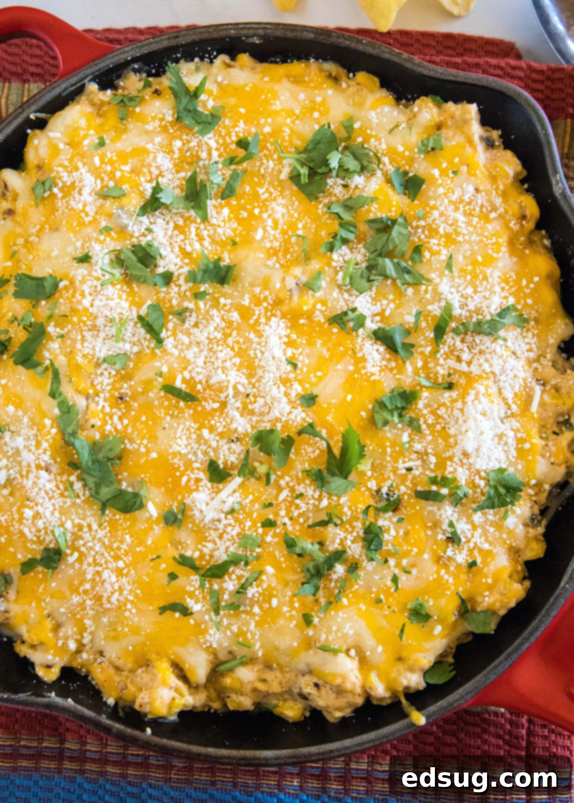 Overhead view of baked street corn dip in a red skillet.