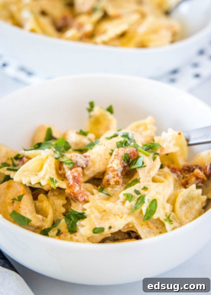 Sun Kissed Tomato Pasta 3 Close-up of creamy sun-dried tomato pasta in a white bowl, showcasing the rich sauce and tender chicken.