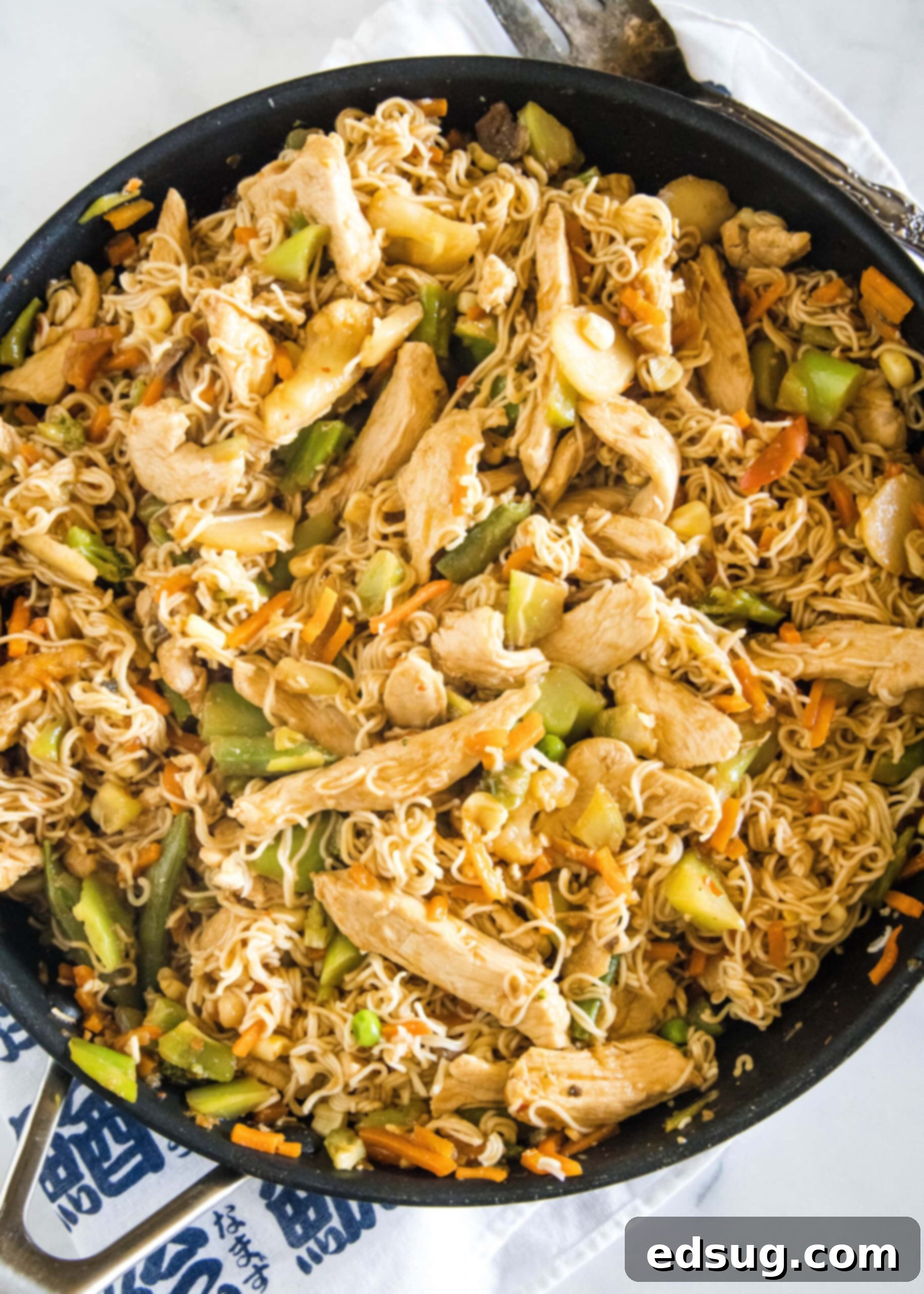 Overhead view of ramen stir fry with chicken and veggies in a skillet. Overhead view of ramen stir fry with chicken and veggies in a skillet, ready to be served.