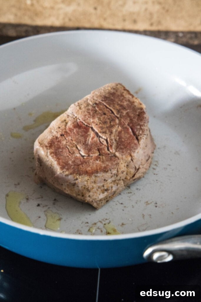 A piece of steak searing in a skillet.