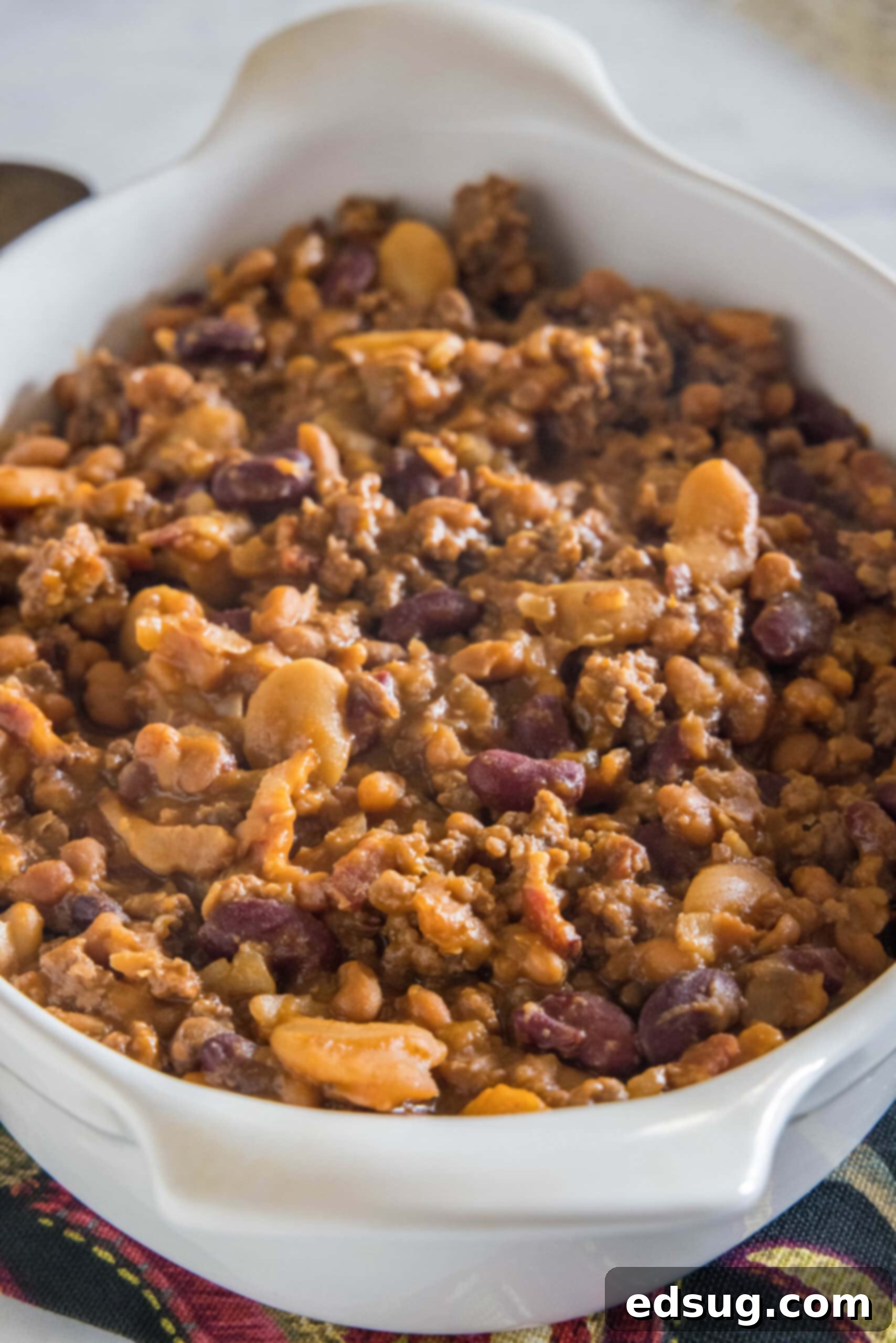 This hearty calico beans recipe is a sweet n' smoky side dish perfect for cookouts, potlucks, and holidays. Make it in the oven or crock pot! Calico beans in a large ceramic baking dish.