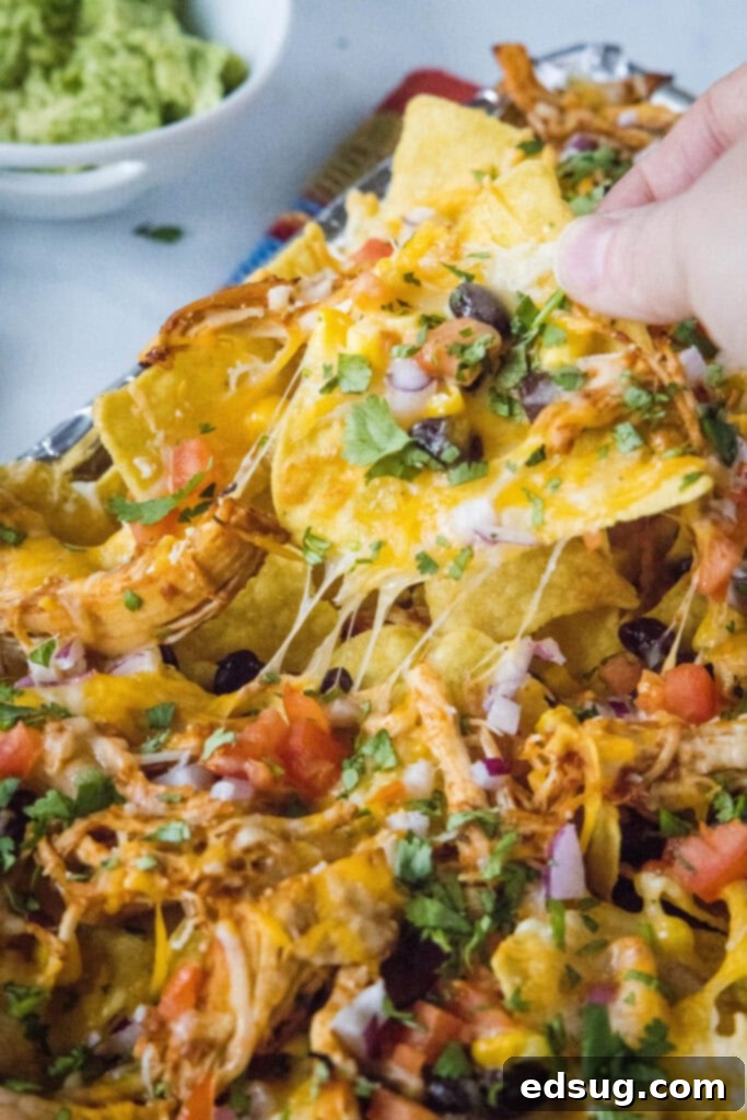 Smoky BBQ Chicken Nachos 7 pulling a chicken nacho off the tray
