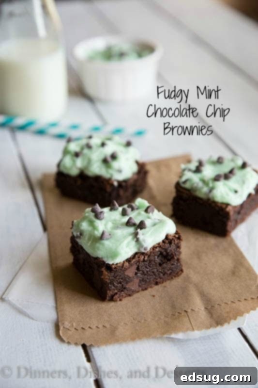 Fudgy mint chocolate chip brownies on a wooden board, showcasing their rich texture and vibrant green frosting