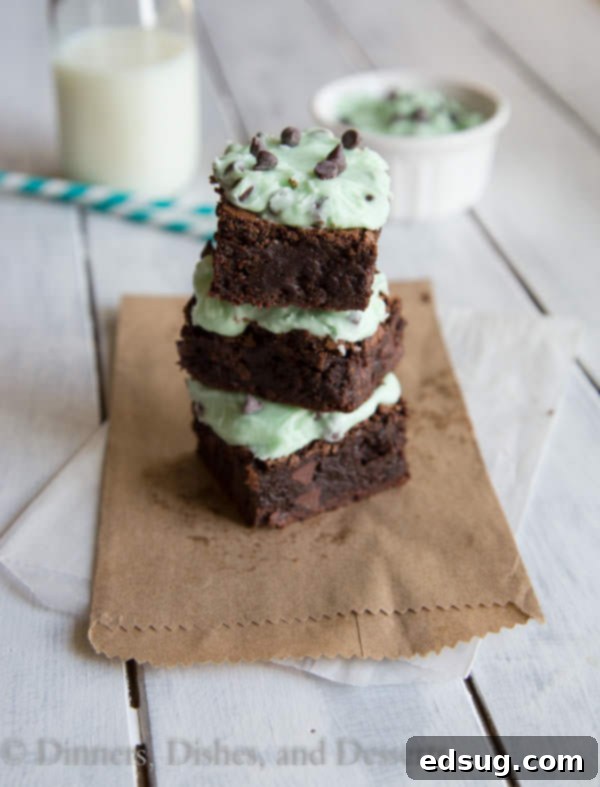 Closeup of fudgy mint chocolate chip brownies on a wooden board, showing a stack of delicious squares