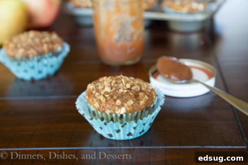 Close-up shot of golden brown whole wheat apple butter muffins on a rustic wooden table.