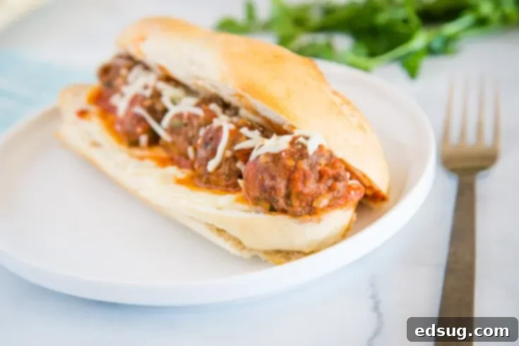 A close up of Bruschetta Meatball Subs with melted cheese and sauce