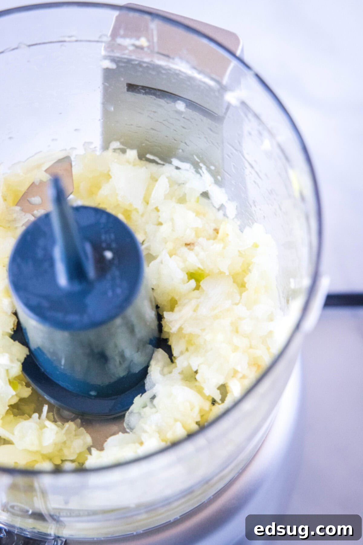 Minced onions, garlic, and ginger in a food processor, ready for the marinade