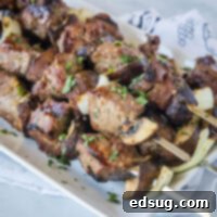 A stack of beef, mushroom, and onion kabobs on a plate
