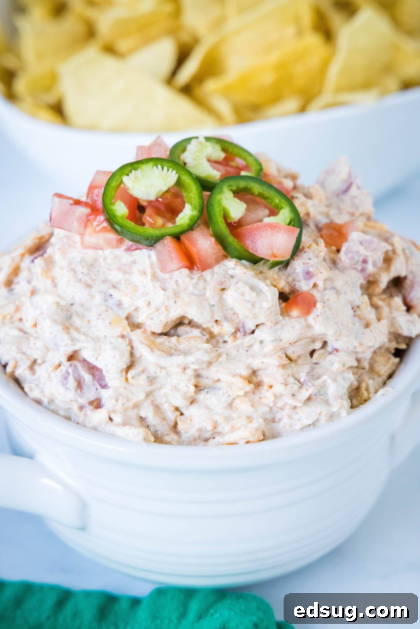 Boat dip is a cool, creamy taco dip inspired by the viral TikTok recipe! It's the perfect easy appetizer for your next summer BBQ or potluck. Boat dip topped with sliced jalapeños in a white bowl, ready to be served with dippers.
