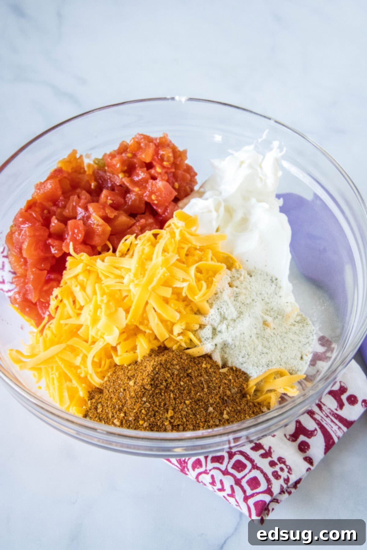 Boat dip is a cool, creamy taco dip inspired by the viral TikTok recipe! It's the perfect easy appetizer for your next summer BBQ or potluck. The five boat dip ingredients combined in a clear glass mixing bowl before stirring.