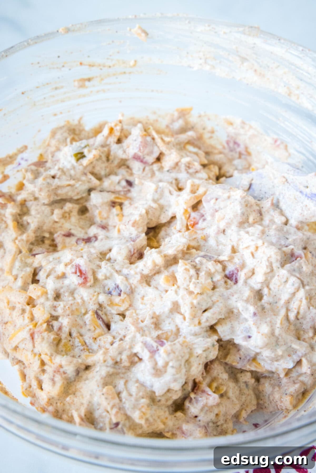 Boat dip is a cool, creamy taco dip inspired by the viral TikTok recipe! It's the perfect easy appetizer for your next summer BBQ or potluck. The boat dip mixed together in a clear glass bowl, showing the creamy texture and diced tomatoes.