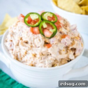 Boating Bliss Dip 2 Boat dip topped with sliced jalapeños in a white bowl, with a bowl of chips in the background.
