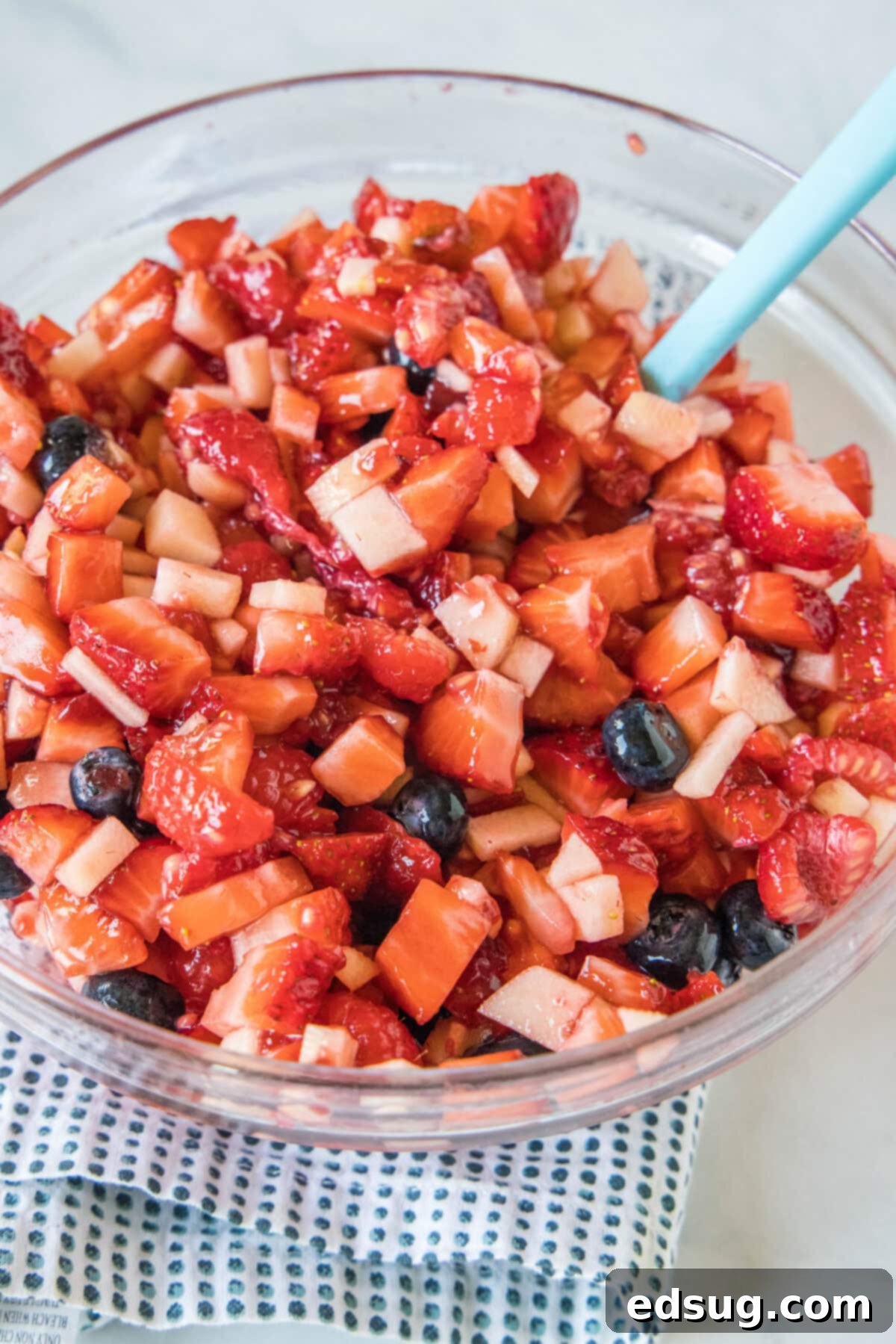 This fruit salsa is a sweet summer salsa recipe bursting with fresh seasonal berries. Serve it with cinnamon chips for a light and easy snack! Fruit salsa in a glass bowl with a stirring spoon.