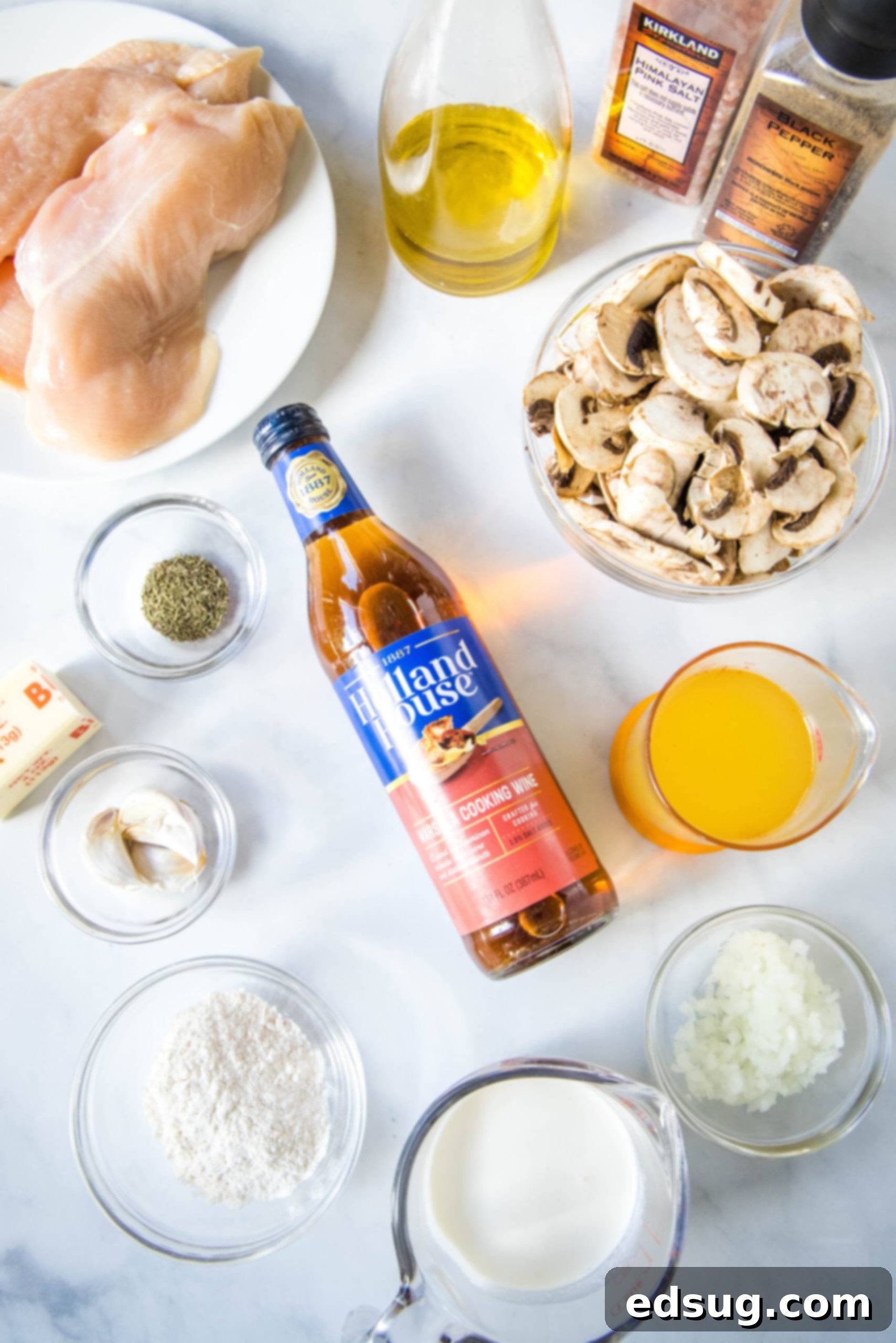 Various ingredients for Chicken Marsala, including chicken breasts, mushrooms, Marsala wine, and fresh herbs, laid out on a kitchen counter.