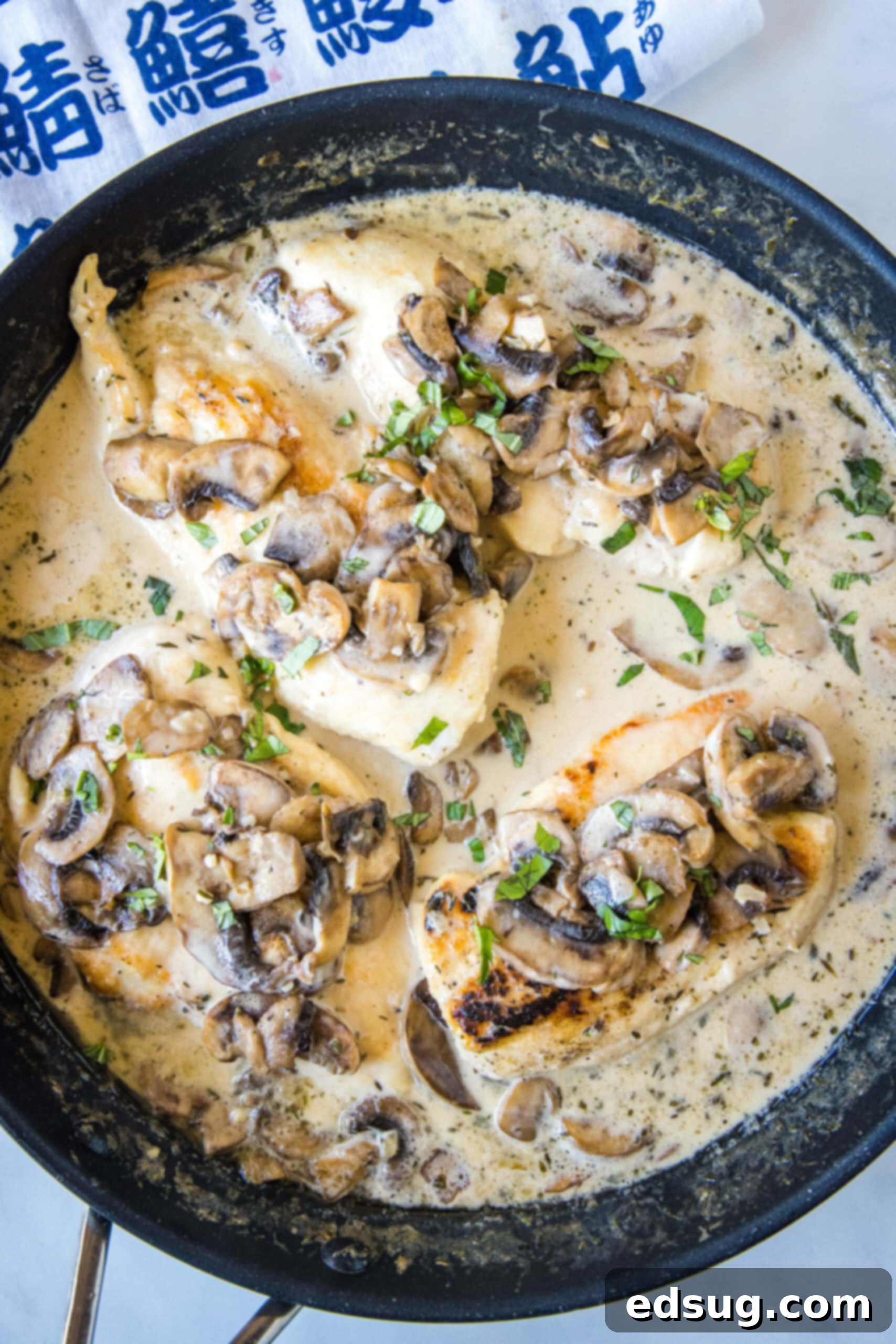 Overhead view of Chicken Marsala covered with a generous amount of creamy Marsala sauce and mushrooms in a skillet, ready to be served.