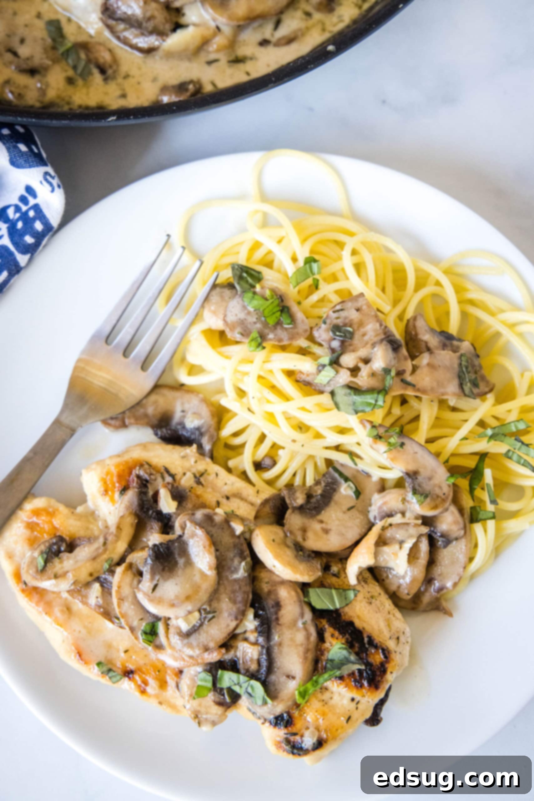Chicken Marsala served on a plate with spaghetti, generously topped with mushrooms and the creamy Marsala sauce, ready to eat.