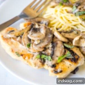 Chicken Marsala served on a plate next to spaghetti, topped with mushrooms.